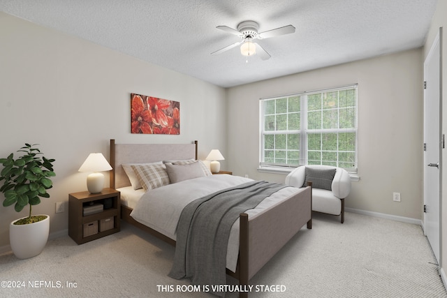 bedroom featuring light colored carpet, a textured ceiling, and ceiling fan