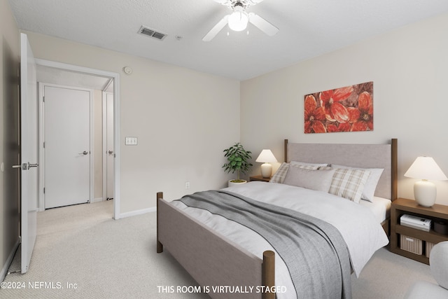 bedroom featuring light colored carpet, a textured ceiling, and ceiling fan