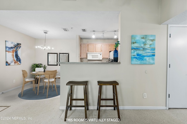 kitchen with light brown cabinetry, hanging light fixtures, light colored carpet, and a notable chandelier