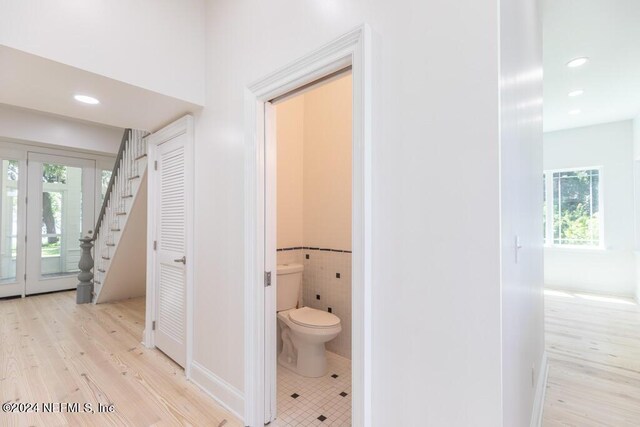 bathroom featuring hardwood / wood-style flooring, tile walls, plenty of natural light, and toilet