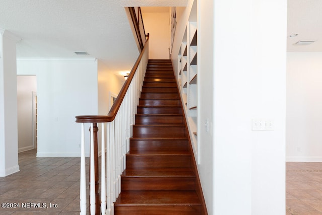 staircase with crown molding and tile patterned floors