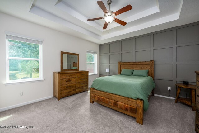 carpeted bedroom with a tray ceiling and ceiling fan