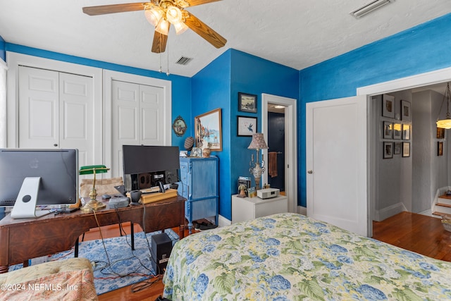 bedroom with ceiling fan, two closets, and wood-type flooring