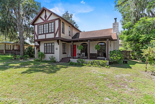 tudor house with covered porch and a front yard