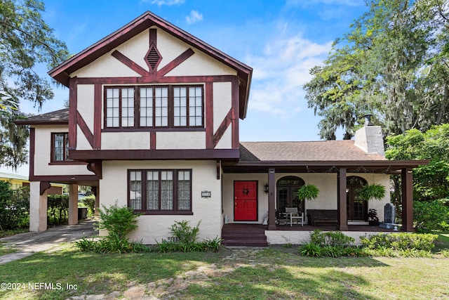 tudor house with a front lawn and covered porch