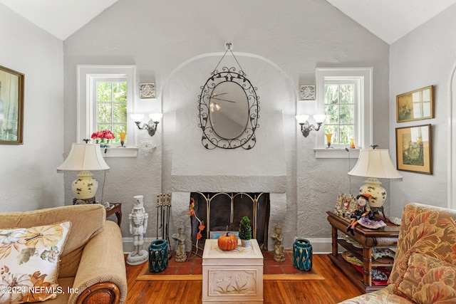 living room featuring hardwood / wood-style flooring, lofted ceiling, and a tile fireplace