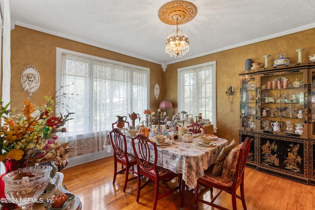 dining area featuring crown molding, a chandelier, light hardwood / wood-style flooring, and a wealth of natural light