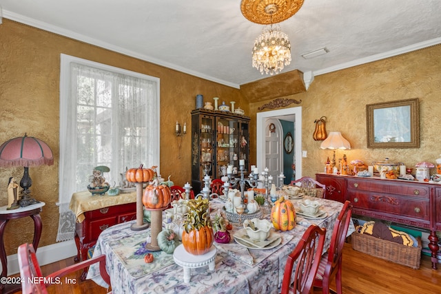 dining area featuring ornamental molding, an inviting chandelier, and hardwood / wood-style floors