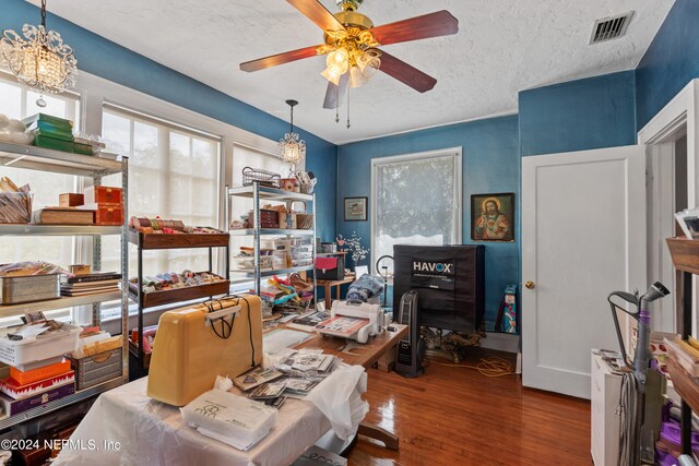 office with ceiling fan with notable chandelier, a textured ceiling, and hardwood / wood-style flooring