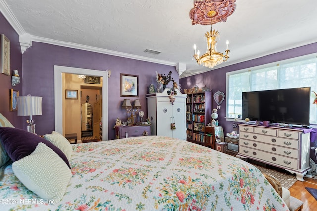 bedroom with a notable chandelier, hardwood / wood-style floors, ornamental molding, and a textured ceiling