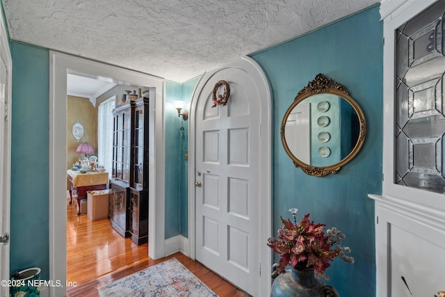 entrance foyer featuring a textured ceiling, wood-type flooring, and crown molding