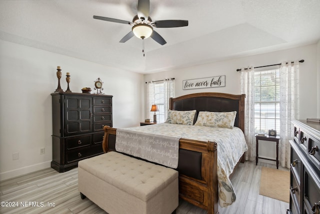 bedroom featuring a tray ceiling, ceiling fan, and light hardwood / wood-style flooring