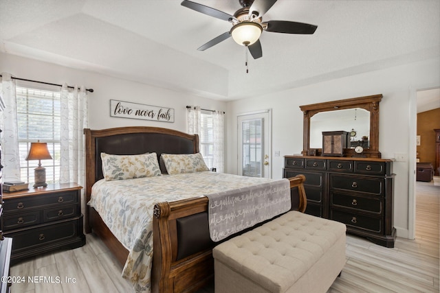 bedroom featuring a raised ceiling, light hardwood / wood-style floors, and ceiling fan