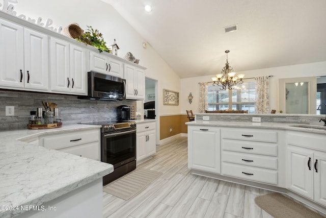 kitchen featuring lofted ceiling, sink, white cabinetry, stainless steel appliances, and a notable chandelier