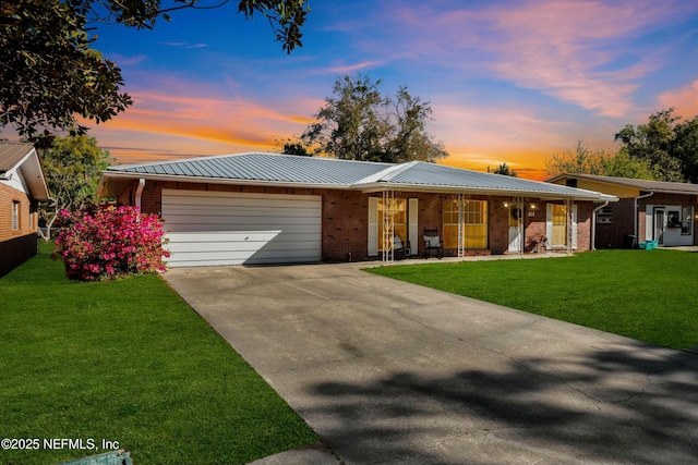 single story home featuring brick siding, an attached garage, concrete driveway, and a yard