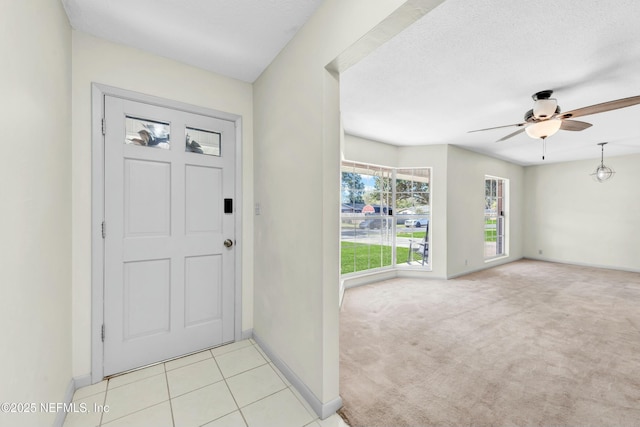 entrance foyer with baseboards, light colored carpet, ceiling fan, and a textured ceiling