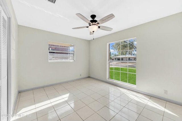 tiled spare room featuring baseboards, a wealth of natural light, and ceiling fan