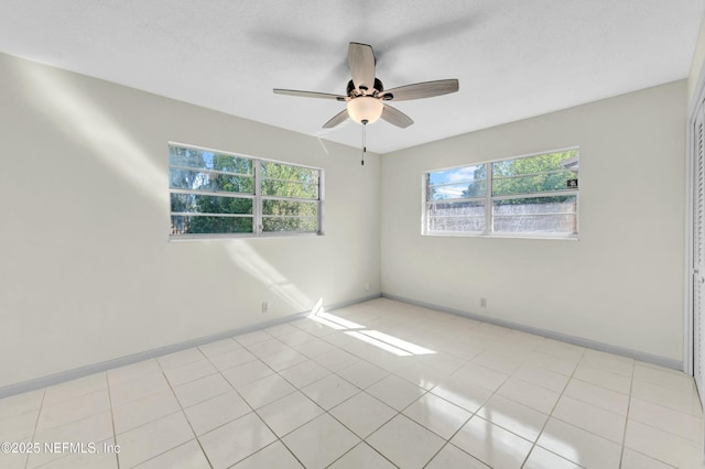 empty room with light tile patterned floors, baseboards, and ceiling fan