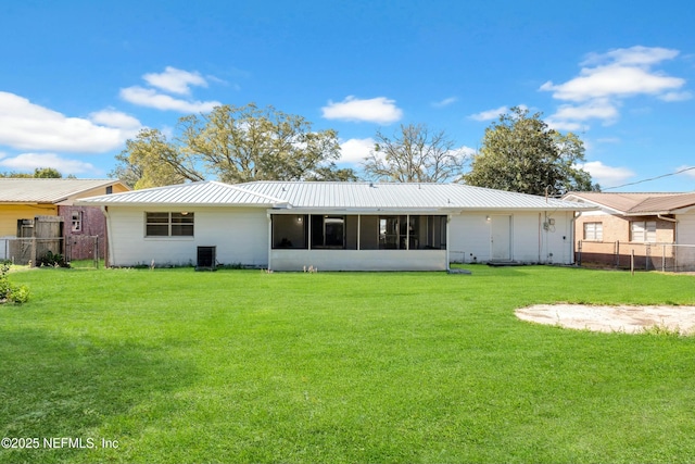 rear view of property featuring a yard, fence, a sunroom, and metal roof