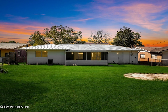 back of property with a yard, fence, and metal roof