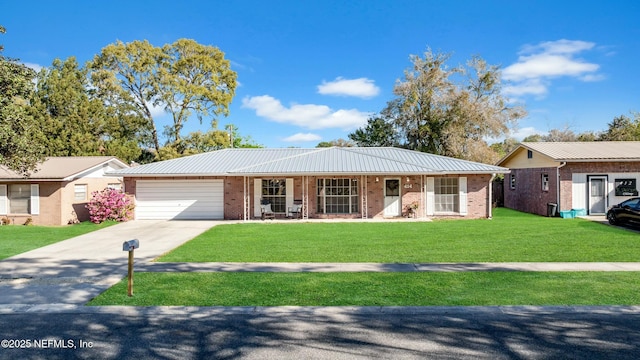 ranch-style house with a front yard, concrete driveway, a garage, brick siding, and metal roof