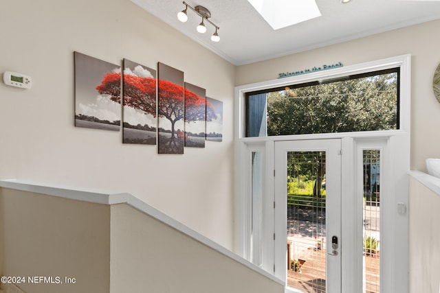 doorway to outside with a skylight, a healthy amount of sunlight, and a textured ceiling