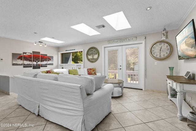 living room with a skylight, light tile patterned flooring, ornamental molding, french doors, and a textured ceiling