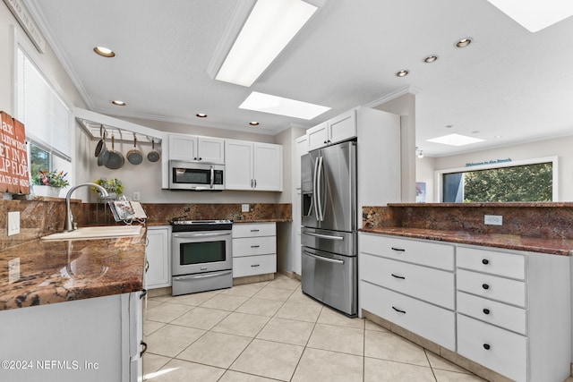 kitchen with white cabinets, a skylight, appliances with stainless steel finishes, and a healthy amount of sunlight