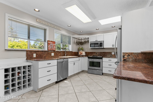 kitchen featuring stainless steel appliances, white cabinetry, plenty of natural light, and sink