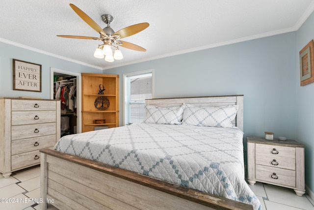 tiled bedroom featuring crown molding, ceiling fan, a walk in closet, and a closet