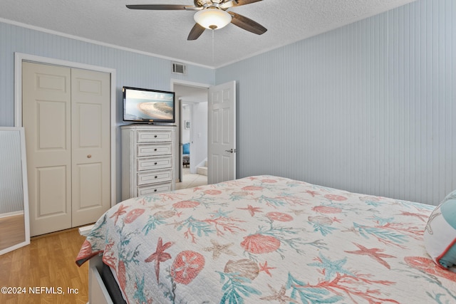 bedroom featuring ceiling fan, a textured ceiling, light hardwood / wood-style flooring, and a closet