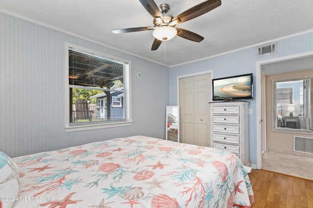 bedroom featuring light hardwood / wood-style floors, ornamental molding, ceiling fan, and a closet