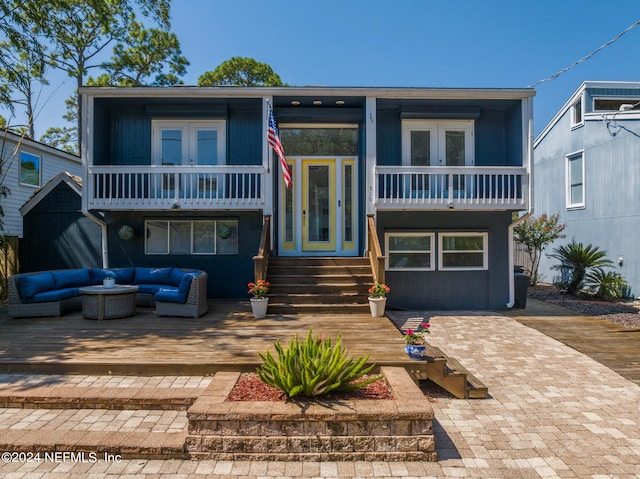 view of front of property with a balcony, an outdoor living space, and french doors