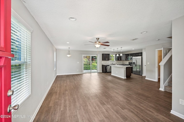 unfurnished living room featuring a textured ceiling, dark hardwood / wood-style flooring, and ceiling fan