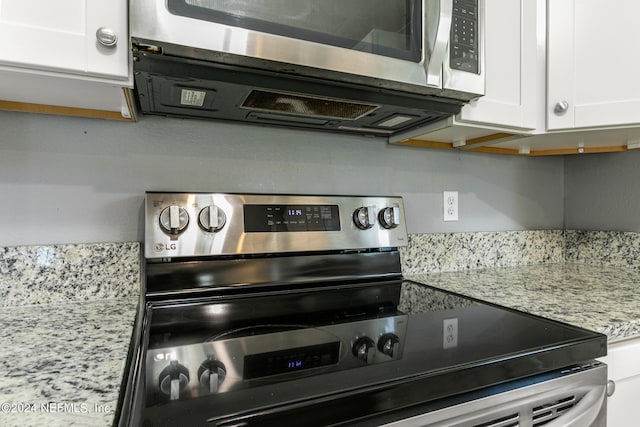 kitchen featuring light stone countertops, stainless steel appliances, and white cabinetry