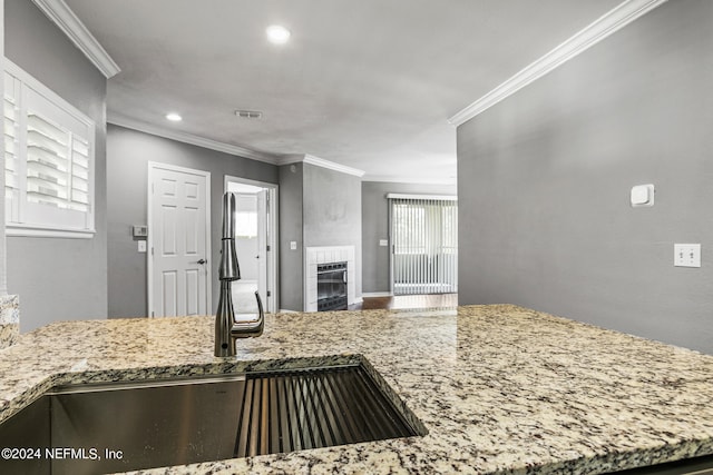 kitchen featuring crown molding, sink, a healthy amount of sunlight, and a tile fireplace