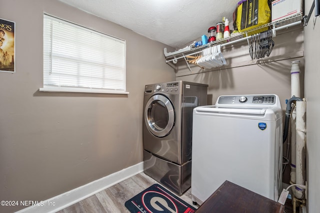 washroom featuring wood-type flooring, washer and clothes dryer, and a textured ceiling