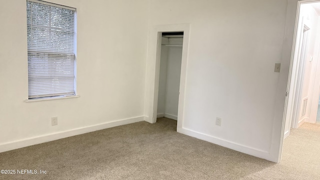 unfurnished bedroom featuring light colored carpet and a closet