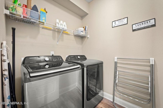 laundry room featuring washing machine and clothes dryer and hardwood / wood-style flooring