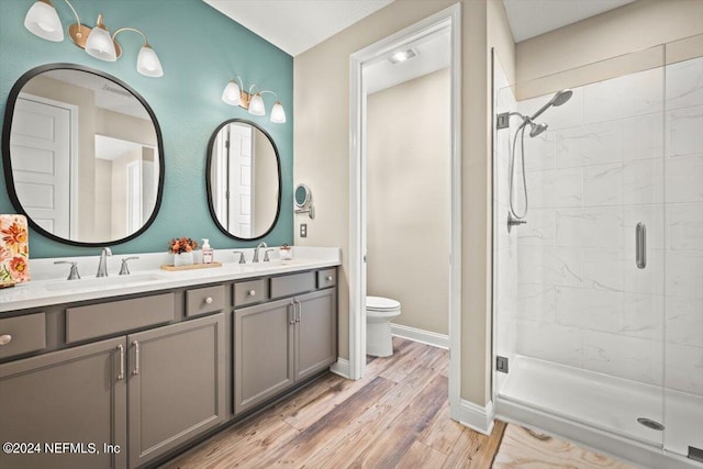 bathroom with hardwood / wood-style flooring, vanity, toilet, and a shower with door