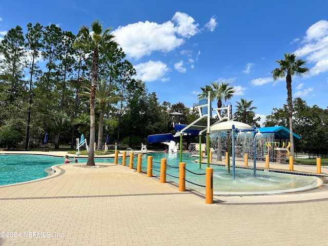 view of swimming pool with pool water feature, a playground, and a water slide