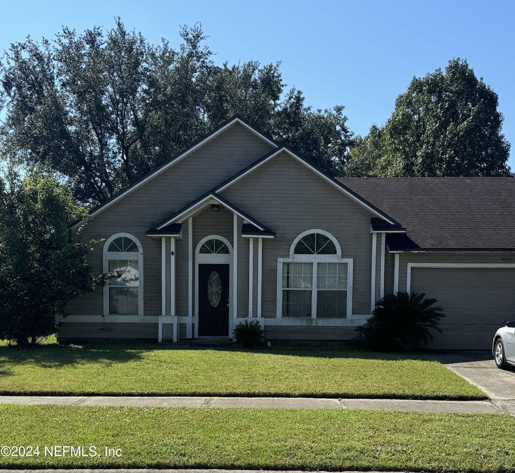 ranch-style house featuring a garage and a front lawn