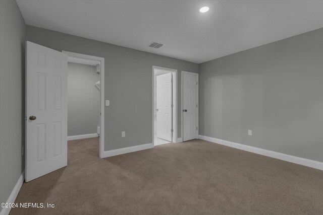 unfurnished bedroom featuring light carpet, a closet, and a spacious closet