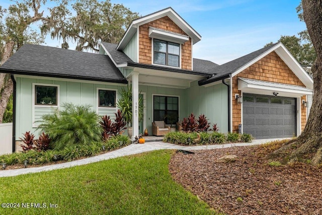 craftsman inspired home with covered porch, a front yard, and a garage