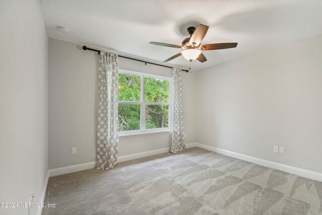 carpeted spare room featuring ceiling fan and a textured ceiling