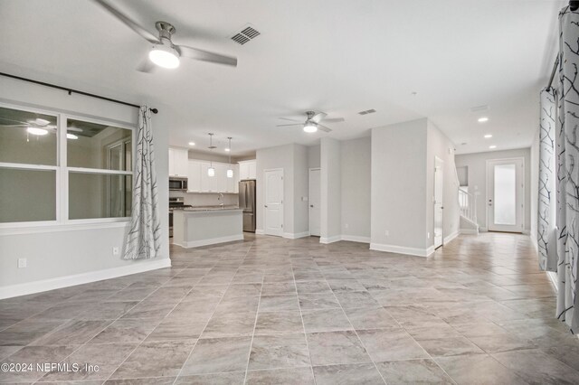 unfurnished living room featuring sink and ceiling fan