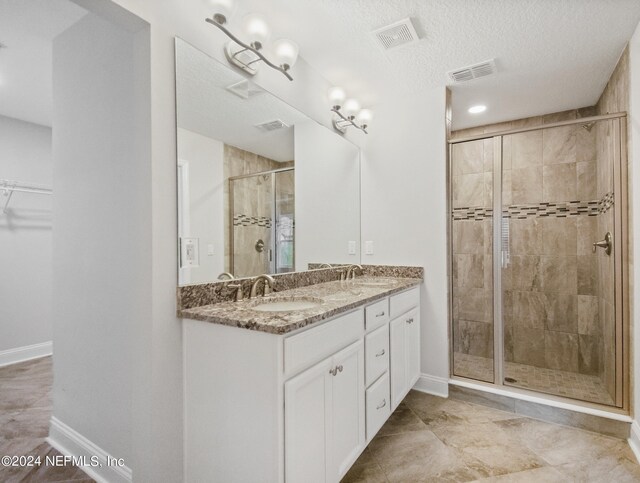 bathroom with tile patterned flooring, a textured ceiling, walk in shower, and vanity