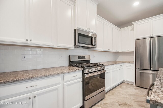 kitchen with light stone counters, appliances with stainless steel finishes, backsplash, and white cabinetry