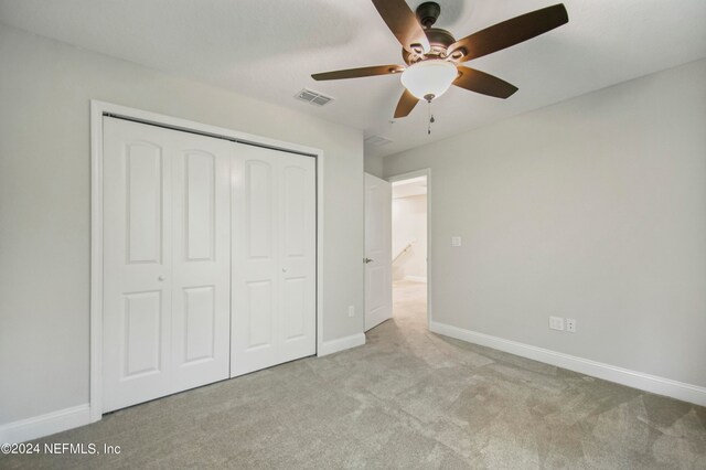 unfurnished bedroom featuring light carpet, a closet, and ceiling fan