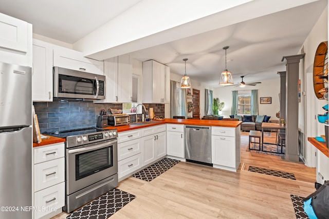 kitchen with ceiling fan, white cabinetry, appliances with stainless steel finishes, light wood-type flooring, and ornate columns